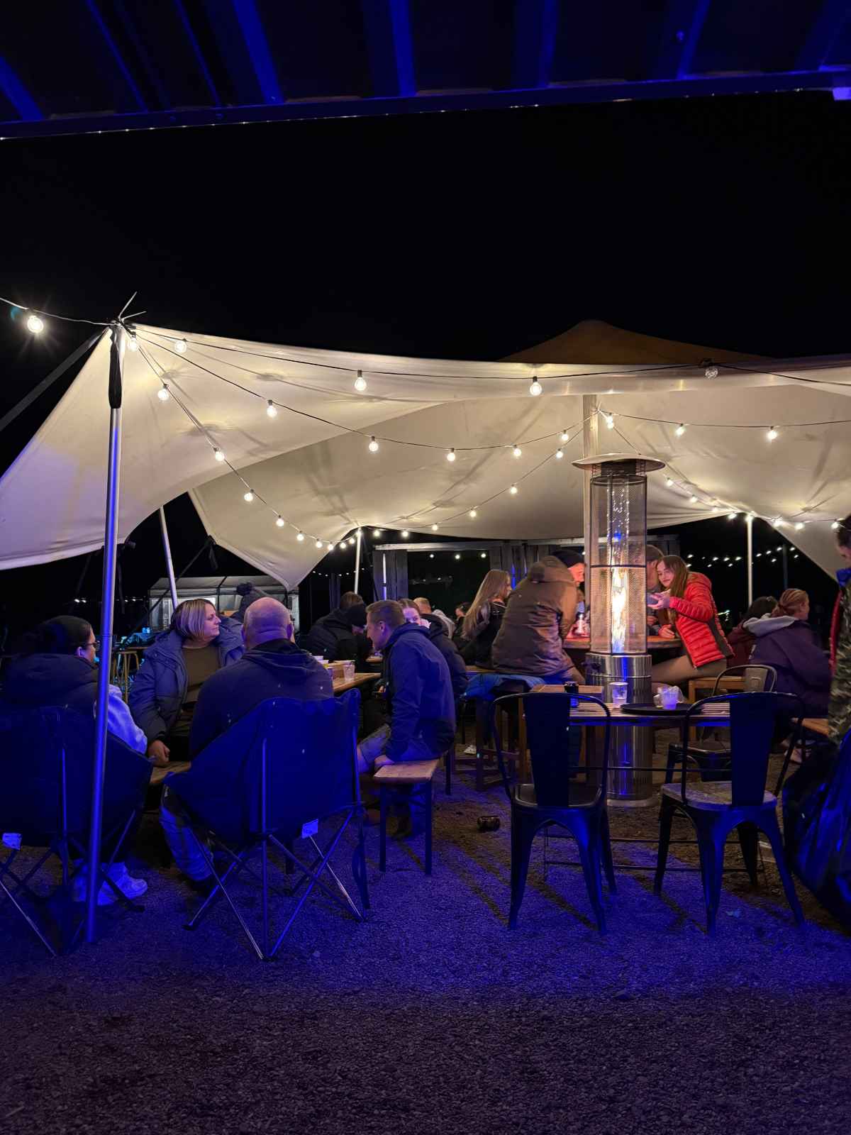 Guests gathered under the stretch tent at The Gin Tin bar on a busy evening at Coast and Castles