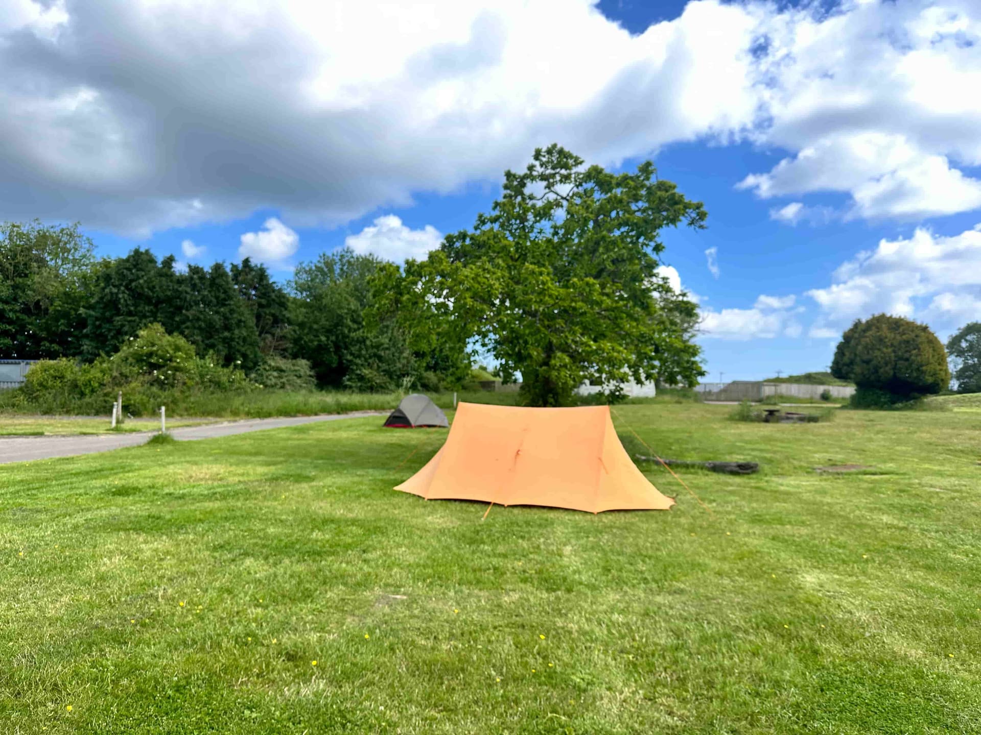 Spacious grass pitches at Coast and Castles with an orange tent and open views
